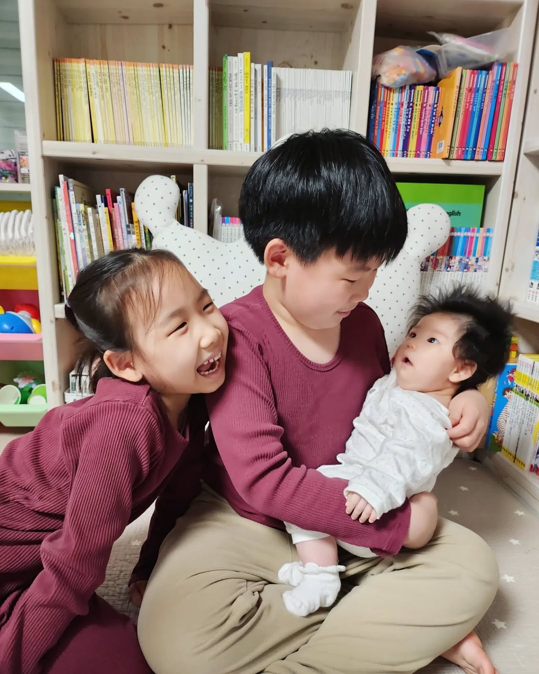 사랑이 듬뿍 담긴 삼남매네 일상: 동생을 포근하게 안아주는 형과 누나의 모습